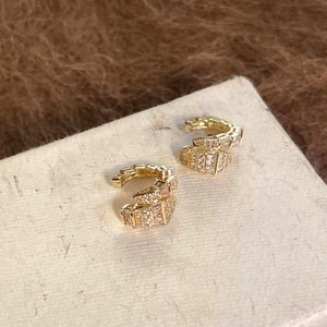 Detail of golden snake-shaped ear cuffs with sparkling zircon pavé for a luxury look.