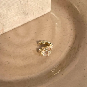 Detailed macro view of an elegant gold snake ear cuff intricately decorated with sparkling zircons.