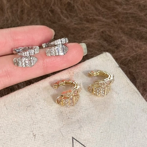 Close-up of sparkling zircon serpent-shaped ear cuffs in gold and silver finish