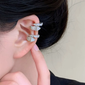 Close-up of sparkling zircon snake-shaped ear cuffs on an ear for a stylish look.