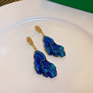 Close-up of vintage style blue textured earrings with gold-tone hardware and intricate details