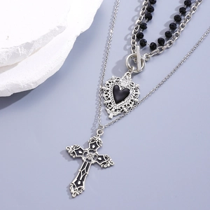 Detail of gothic layered necklace with cross and black heart pendant on purple background