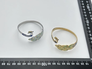 Detail of retro peacock open cuff bangle with enamel feathers in gold and silver plating