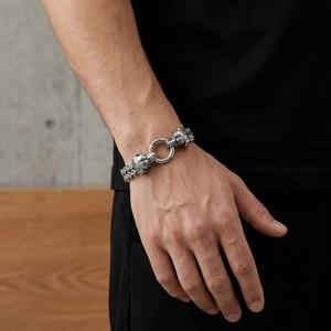 Close-up of a silver punk wolf head bracelet with woven chain and ring clasp on wrist