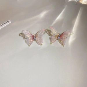 Vue détaillée des boucles d'oreilles papillon en tissu rose avec cristaux et aiguilles en argent.