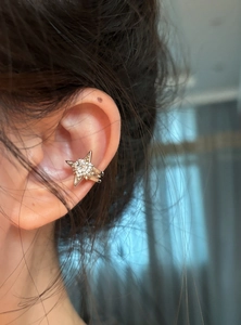 Close-up detail of a sparkling silver star ear cuff with zircon crystals worn on ear
