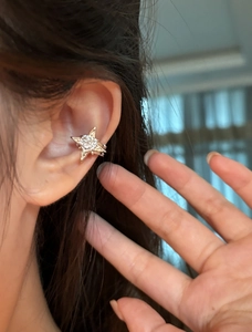 Detailed close-up showing a sparkling star-shaped zircon ear cuff worn on a female ear bone.