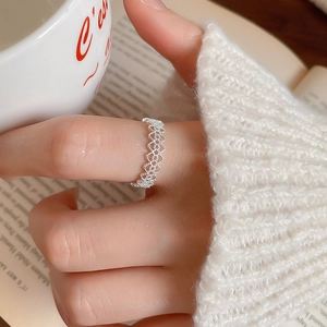 Detail view of an elegant sparkling silver lace-patterned geometric ring on a finger