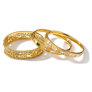 Detail shot of three golden stainless steel bangles with zircon inlays and hollowed patterns.