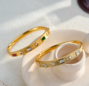 Detail shot of gold-plated stainless steel bangles with geometric zircon inlays.
