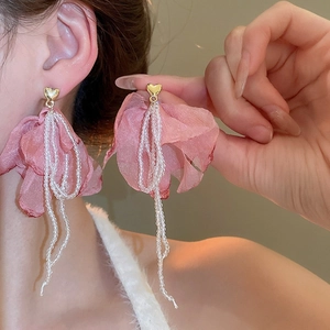 Close-up view of elegant pink chiffon flower tassel earrings worn by a model in detail
