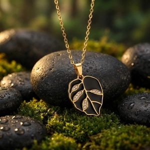 Close-up of black enamel leaf pendant with rhinestones on a gold stainless steel chain