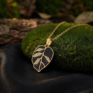 Exquisite close-up of a black enamel leaf pendant necklace with rhinestones on moss