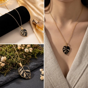 Detailed view of a gold leaf pendant necklace with black enamel and crystal accents.