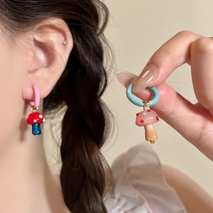 Detalle de los pendientes de aro asimétricos con colgante de hongo en esmalte de colores