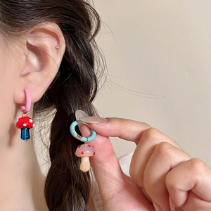 Vista de cerca de pendientes de aro asimétricos con colgantes de setas de colores