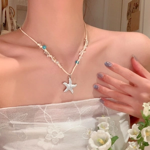 Detail showing a white starfish shell beaded woven necklace on a woman's neck.