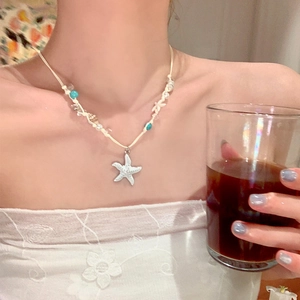 Close-up of woven starfish bead necklace with turquoise accents worn by a model