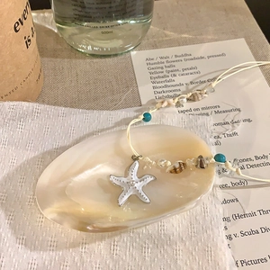 Close-up of handmade starfish and shell beaded woven necklace for beach vacation