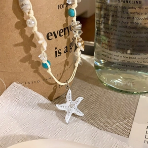 Macro view of a beach-style beaded necklace with white starfish pendant and shells.