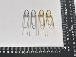 Detailed view of silver and gold tassel earrings with teardrop hollow studs and long chains
