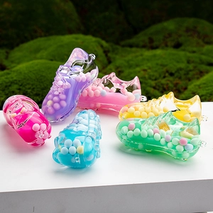 Close-up of six colorful acrylic soccer shoe pendants with sand filling on green moss