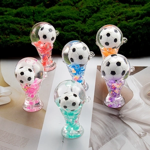 Detail view of six colorful acrylic soccer trophy keychains on a green moss surface