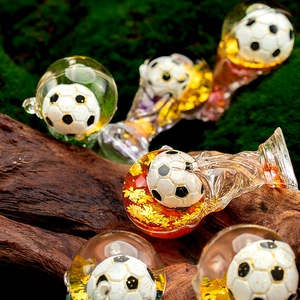 Macro detail of acrylic quicksand football keychain with gold flakes and trophy elements