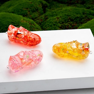 Close-up of three soccer shoe liquid acrylic charms with colorful glitter inside