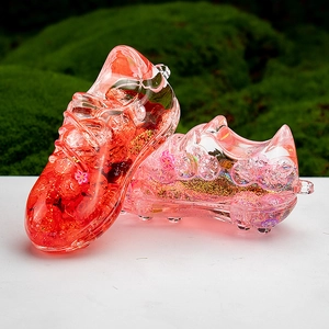 Detailed close-up of pink liquid-filled acrylic soccer shoe keychain with glitter and sequins