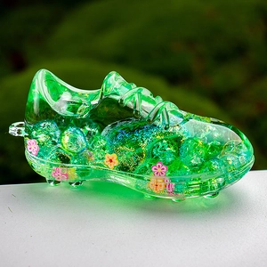 Detailed side view of green acrylic soccer cleat keychain with colorful glitter fillings