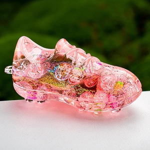Macro detail of pink acrylic soccer shoe keychain with glitter and golden quicksand