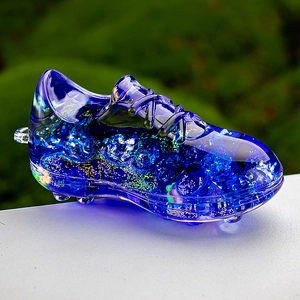 Close-up of blue liquid-filled acrylic soccer shoe keychain with sparkling gold sequins