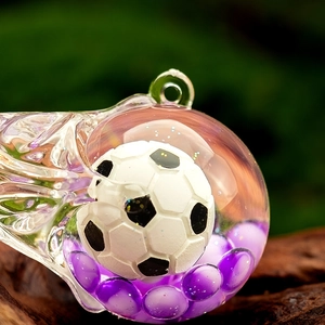 Macro shot of liquid motion football trophy keychain with purple beads and clear orb