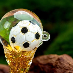 Detailed close-up of a football acrylic quicksand keychain with golden glitter details