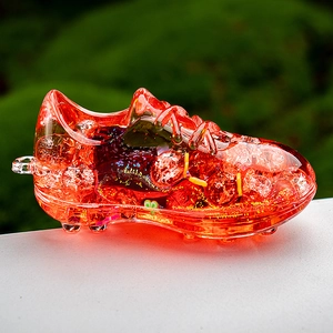 Detail of a bright orange acrylic soccer cleat keychain with floating glitter and liquid