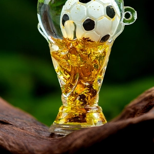 Macro shot of trophy-shaped acrylic keychain with golden fluid and miniature soccer ball