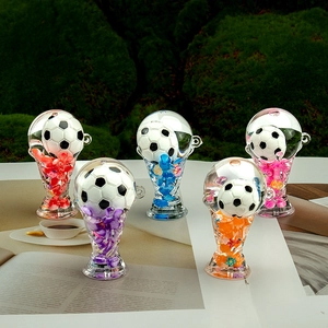 Five colorful trophy keychains with football miniatures on a book over grass