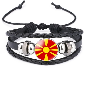 Macro detail of multi-layer black leather bracelet with North Macedonia flag glass charm