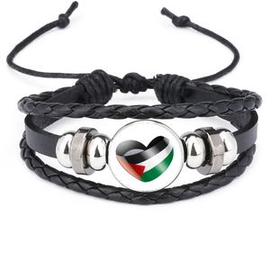 Macro detail of Palestine flag heart glass cabochon on braided black leather bracelet