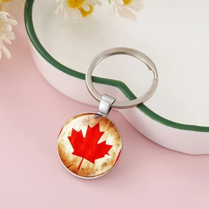 Detailed shot of Canadian flag maple leaf keychain on a white porcelain plate décor