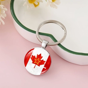 Close-up of a silver-toned Canadian flag maple leaf charm keychain with glass dome