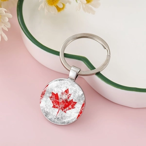 Macro detail of Canada flag maple leaf glass dome keychain in a white ceramic dish