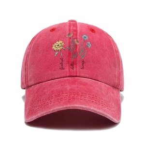 Detail of vintage red washed cotton baseball cap featuring floral embroidery and script text