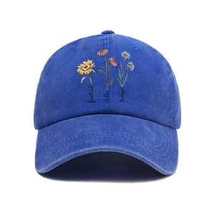 Detail of washed navy denim baseball cap with foxtrot delta tango floral embroidery