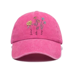 Detailed view of floral prints and embroidered text on a rose red vintage cotton baseball cap