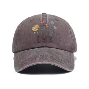 Detailed view of washed grey cotton baseball cap with floral embroidery and text