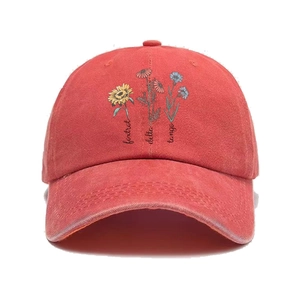 Close-up of red washed cotton baseball cap featuring floral embroidery and text details
