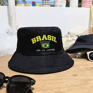 Black Brazil flag bucket hat with yellow Brasil text on a wooden outdoor surface