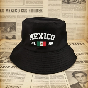Détail d'un bob mexicain en toile noire avec drapeau et inscription EST. 1810